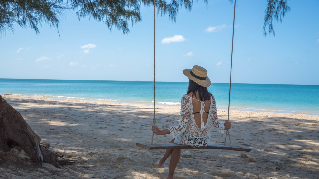 woman at the beach and sitting on a swing