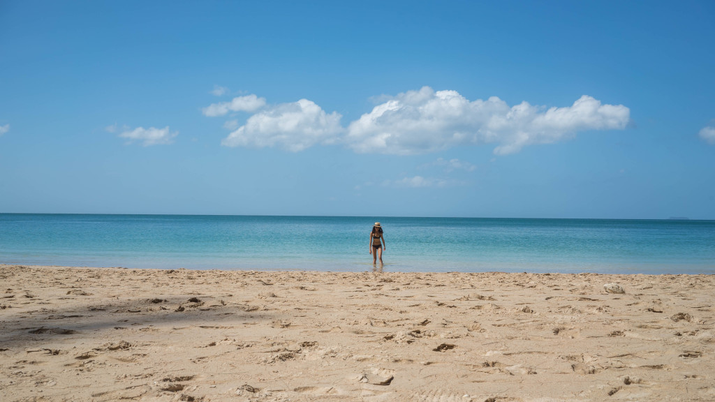 woman at the beach wearing a two piece swimsuit and wearing a hat