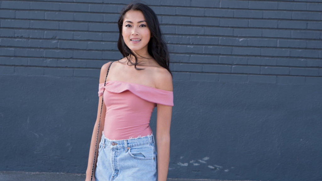 woman smiling and wearing Reformation Classon Bodysuit, Urban Outfitters Denim Skirt