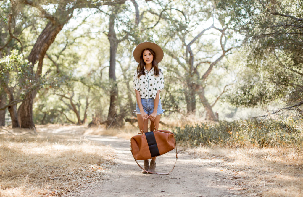 woman in the outdoors and holding a leather brown bag