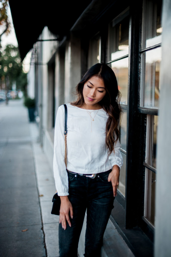 woman looking down and wearing white top, jeans, and fall style restricted shoes 