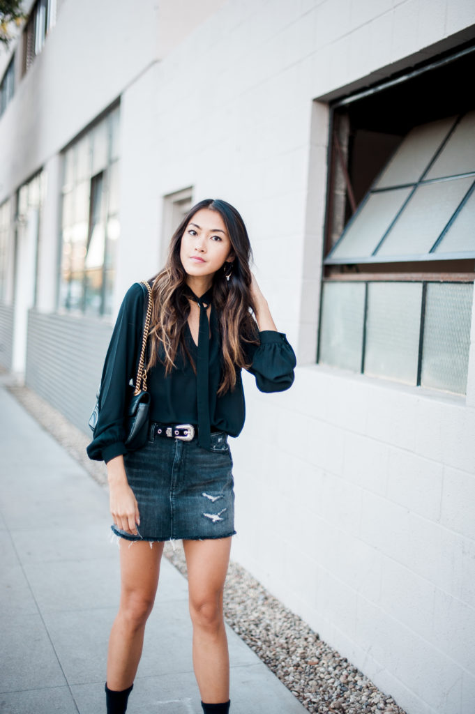 woman wearing black top and denim skirt, touching her heart and sharing Blogs Even Matter Anymore