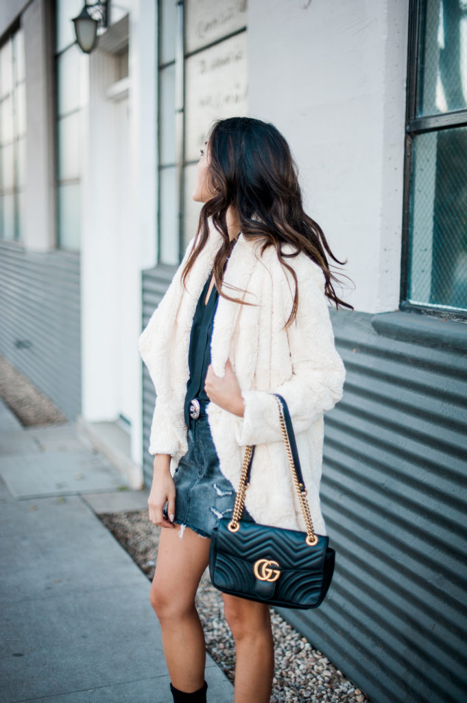 woman wearing black long sleeves top, denim skirt, and jacket 