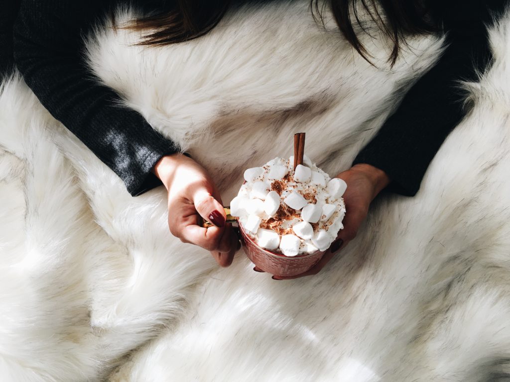 person holding a hot drink with marshmallows 