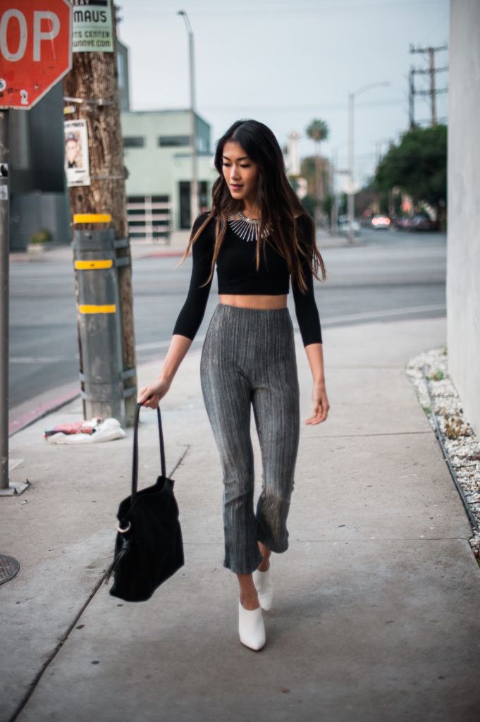 woman in black top, Party Pants, and holding a black bag