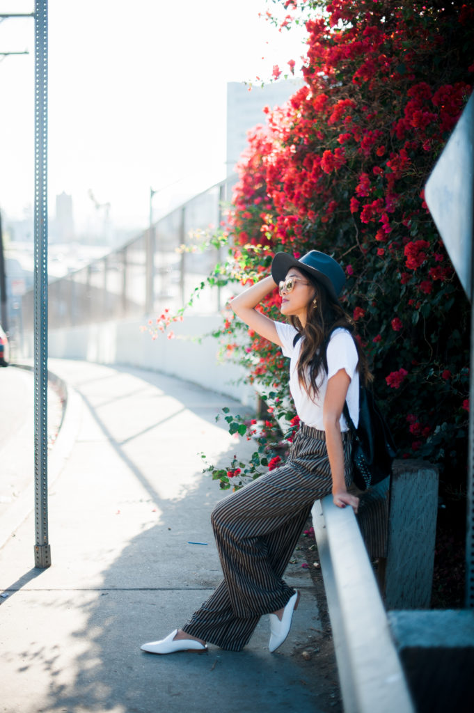 woman in building a thoughtful wardrobe with hat, white shirt, and wide pants