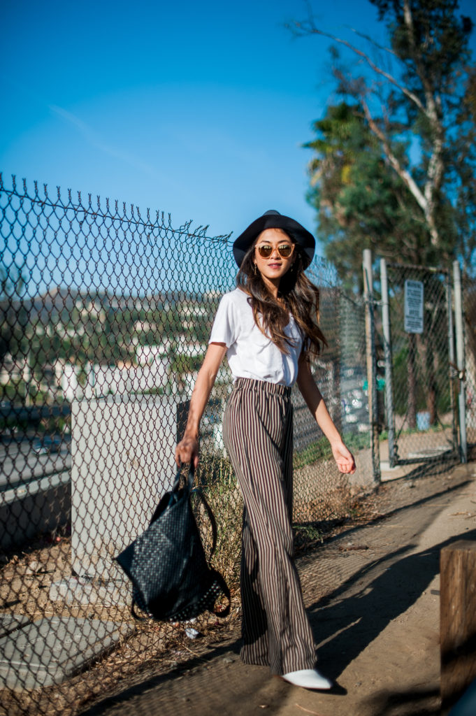 woman in a thoughtful wardrobe with hat, white shirt, and wide pants