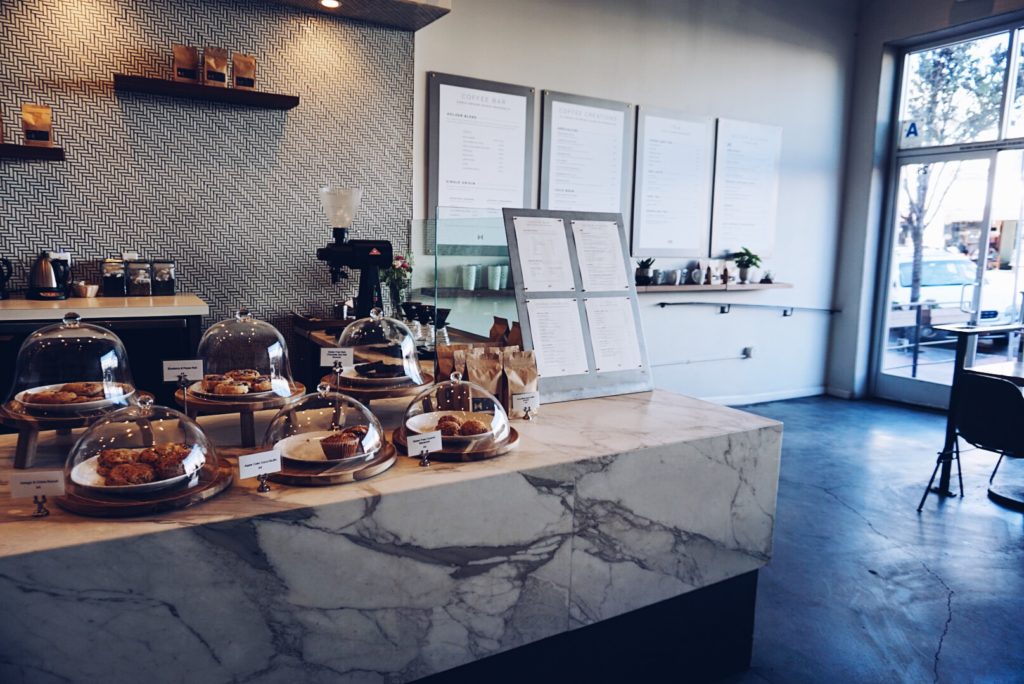 cupcakes on display, menu, and coffee inside a cafe