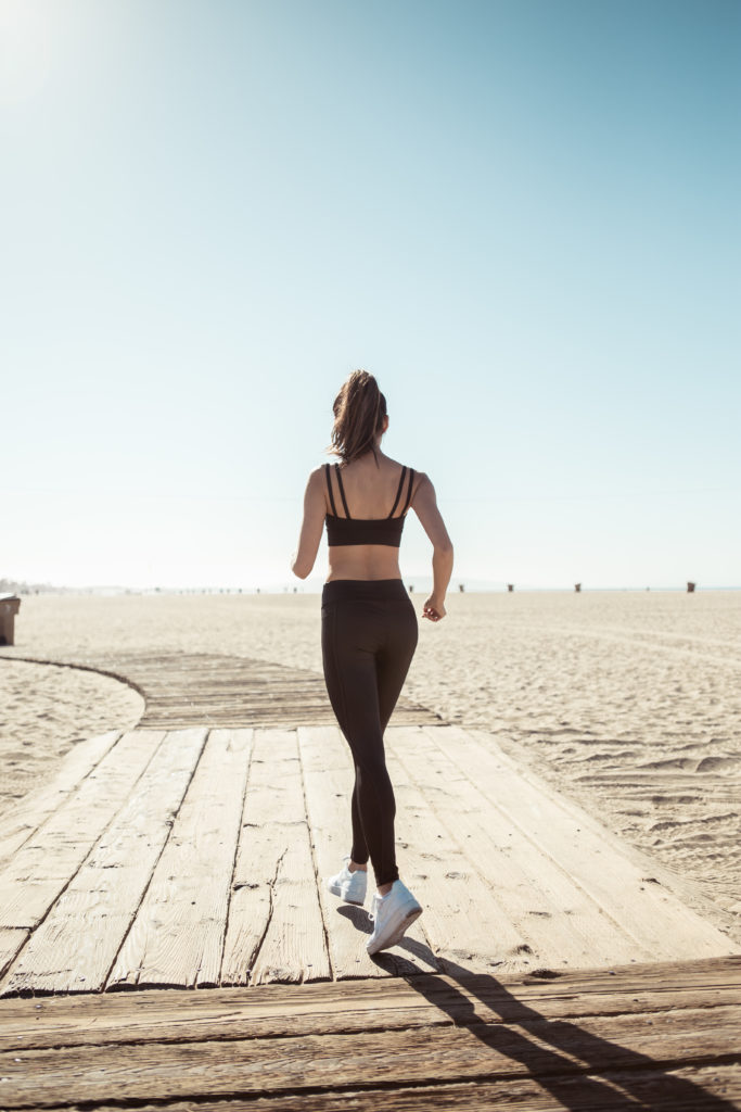 woman jogging at the beach wearing all black sportswear