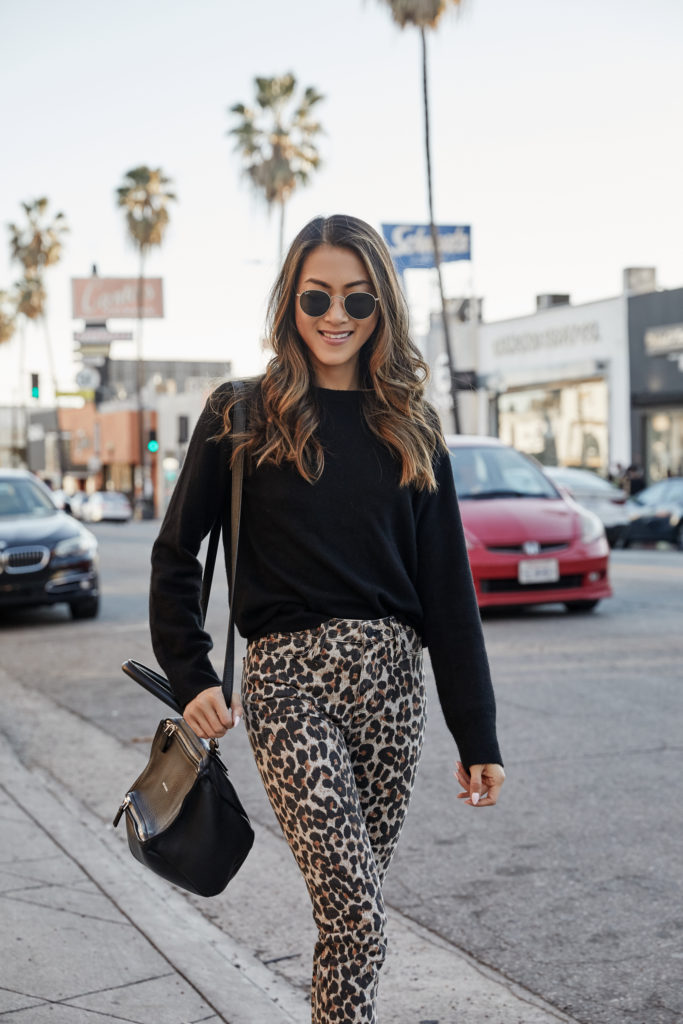 woman smiling and wearing sweater: equipment, pants: paige , bag: givenchy, sunnies: ray-ban 
