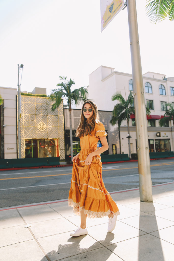 a dress that has a country style to it in a mellow and mustardy yellow worn by a girl that is teaching how you can reduce your carbon footprint as an influencer